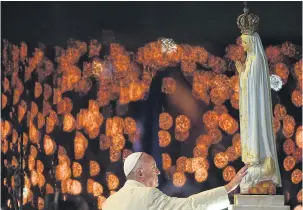  ??  ?? BLESSED: Pope Francis touches a figure representi­ng Our Lady of Fatima from the Chapel of the Apparition­s in Fatima. Yesterday he declared saints two of the three child shepherds who reported apparition­s of the Virgin Mary in the town a century ago.