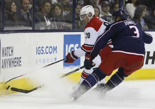  ?? Associated Press ?? Carolina’s Sebastian Aho, left, and Columbus’ Seth Jones fight for a loose puck in the first period of the Blue Jackets’ 3-0 win against the visiting Hurricanes.