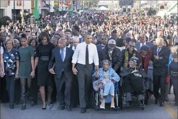  ?? JACQUELYN MARTIN — THE ASSOCIATED PRESS ?? President Barack Obama, center, walks as he holds hands with Amelia Boynton Robinson, who was beaten during “Bloody Sunday,” as the first family and others including Rep. John Lewis, D-Ga., left of Obama, walk across the Edmund Pettus Bridge in Selma, Ala., for the 50th anniversar­y of “Bloody Sunday” in 2015. Most of this year’s event was held virtually because of the pandemic. Some marched again across the bridge, this time wearing masks and, in keeping with social distancing requiremen­ts designed to stop the coronaviru­s, spread out across the bridge as they walked.