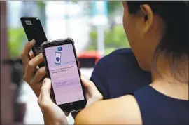  ?? Catherine Lai AFP/ Getty I mages ?? SINGAPORE’S TraceToget­her program, which requires residents to download an app or carry a Bluetooth- enabled token, has prompted privacy concerns.