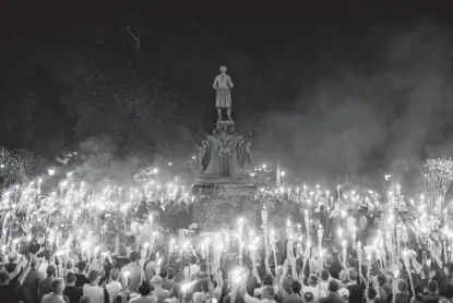  ?? Edu Bayer / New York Times file photo ?? Torch-bearing white nationalis­ts rally around a statue of Thomas Jefferson near the University of Virginia campus in Charlottes­ville two years ago today.