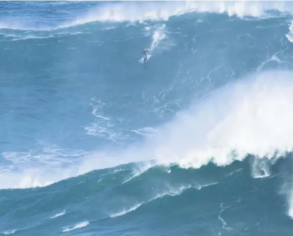  ??  ?? > ‘The waves were reaching between 60 and 80ft-plus’ – Glyn Ovens, 38, surfing huge waves in Nazare, Portugal, on New Year’s Day