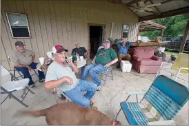  ?? Staff photo by Evan Lewis ?? Carlos Morison and others spend one last get-together Saturday at the riverside home of Robert Bibby in Garland City. Water from the rising Red River began entering a garage on the property earlier in the day, and the group believes Bibby’s home will...