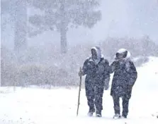  ?? WILL LESTER/THE ORANGE COUNTY REGISTER VIA AP ?? Right: Wrightwood, Calif., residents Nick and Christine Hoban enjoy a walk Monday as heavy snow falls.