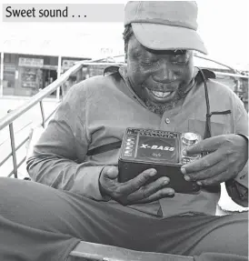  ??  ?? A pushcart operator Mr Misheck Sibanda enjoys a programme from a radio that he moves about with strapped on his shoulder while waiting for clients at a city supermarke­t along Fort Street in Bulawayo recently