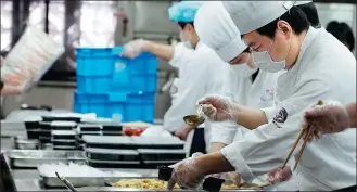  ?? LIU YING / XINHUA ?? Chefs prepare meals in a restaurant kitchen in Shanghai for takeout delivery to nearby companies and employees on Tuesday.