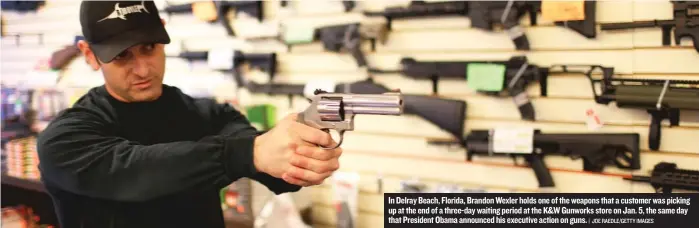  ?? | JOE RAEDLE/GETTY IMAGES ?? In Delray Beach, Florida, BrandonWex­ler holds one of the weapons that a customer was picking up at the end of a three-daywaiting period at the K&WGunworks store on Jan. 5, the same day that President Obama announced his executive action on guns.