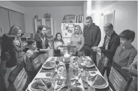  ?? John Moore / Getty Images ?? Central American immigrants and their families pray before Thanksgivi­ng dinner in Stamford, Conn. Family and friends came together in an apartment to celebrate the holiday with turkey and Latin American dishes.