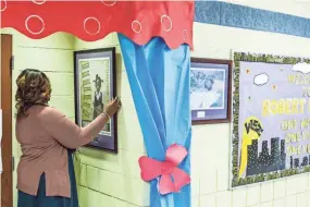  ??  ?? Dr. Janice Tankson, principal of Robert R. Church Elementary School, adjusts one of the many pieces of art that are on the school's hallway walls while giving a tour on May 1. BRAD VEST/THE COMMERCIAL APPEAL