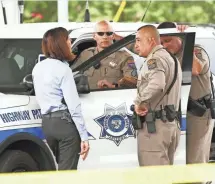  ?? ROB SCHUMACHER, THE REPUBLIC ?? Public safety officers huddle after a white pickup was hit by gunfire in the rear passenger window on Interstate 10 in Phoenix on Wednesday. There have been 11 shootings.