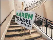  ?? CURTIS COMPTON/CCOMPTON@AJC.COM ?? Andrea Tenjo sets out a sign for Karen Handel’s election night party. Handel is Georgia’s first female Republican U.S. House member