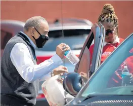  ?? TELECHAN/POST-TRIBUNE PHOTOS KYLE ?? State Rep. Vernon Smith, D-Gary, hands a meal to a visitor as members of the Greater St. Stephen Missionary Baptist Church and volunteers pass out Easter dinners Sunday.