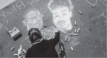  ?? BRANDON BELL Getty Images ?? A woman draws a portrait of George Floyd and Daunte Wright in the intersecti­on in Minneapoli­s, Minnesota. People gathered during the Black & Yellow Solidarity With Asian Lives demonstrat­ion to honor the lives of Floyd and Wright. Protests and demonstrat­ions continue around Minneapoli­s following the fatal shooting of 20-year-old Daunte Wright by a Brooklyn Center police officer.