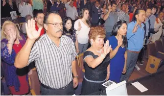  ?? MARLA BROSE/JOURNAL ?? A group of 146 people from 36 countries raise their right hands as they take the Oath of Allegiance on Wednesday, becoming new U.S. citizens. From front left are Joel Tarin, Teresa Najera and Bijena Adhikari.