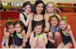  ??  ?? At Dynamo Gymnastics in Cambridge, Victoria Moors now helps guide the next generation of athletes. Taking a break from training to pose with their coach are Adele Parker, top left, and Kayssie Aebersold, top right. In front, from the left, Isabella...