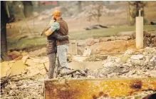  ??  ?? Chris and Nancy Brown embrace while searching the remains of their home in Paradise, California, on Monday.