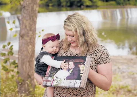  ?? CHARLIE RIEDEL/AP ?? Aubrea Baker, with her daughter Haylen, visits her late husband’s favorite fishing spot in Burlington, Kansas.