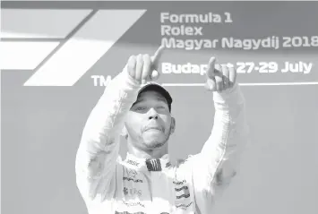  ?? AGENCE FRANCE PRESSE ?? Mercedes' British driver Lewis Hamilton reacts as he celebrates on the podium after winning the Formula One Hungarian Grand Prix at the Hungarorin­g circuit in Mogyorod near Budapest, Hungary.