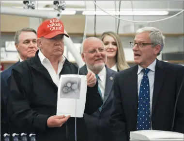  ?? HYOSUB SHIN - ASSOCIATED PRESS ?? President Donald Trump holds a photograph of coronaviru­s as Dr. Steve Monroe,right, with CDC speaks to members of the press at the headquarte­rs of the Centers for Disease Control and Prevention in Atlanta on Friday. President Trump’s trip to the Centers for Disease Control and Prevention, briefly scuttled Friday because of unfounded fears that someone there had contracted the coronaviru­s, was back on, giving the president another chance to calm growing alarm about the spread of the virus in America.