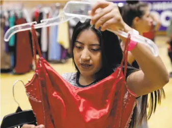  ??  ?? Above: Vivian Yan (left) and Melanie Thai check out pictures they took in various dresses before making a choice. Below: Zoila Lopez tries to pick a dress at the event put on by Lesley West, the Oakland Education Fund, the school district and the...