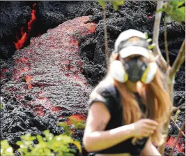  ?? MARIO TAMA / GETTY IMAGES ?? Lava flows at a new fissure in the aftermath of eruptions from the Kilauea volcano on Hawaii’s Big Island as a local resident in a gas mask walks nearby after taking photos. The U.S. Geological Survey said a recent lowering of the lava lake at the...