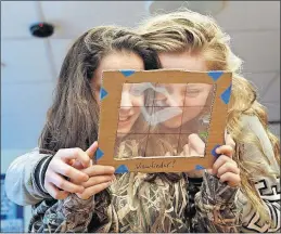  ??  ?? Fifth-graders McKinsey Mitchell, left, and Mackenzie Herder use a framing tool to practice composing photos as part of the public-art project.