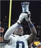  ?? DARRON CUMMINGS/AP ?? Michigan defensive back Mike Sainristil holds the MVP trophy after the Big Ten title game against Iowa on Dec. 2.
