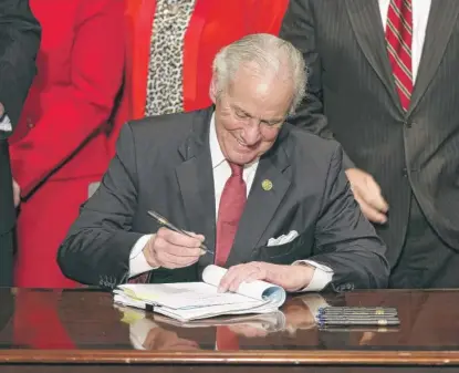  ?? JEFFREY COLLINS/AP ?? South Carolina Gov. Henry McMaster signs into law a measure Feb. 18 banning almost all abortions in that state. Planned Parenthood filed a federal lawsuit to stop the South Carolina Fetal Heartbeat and Protection from Abortion Act from taking effect.