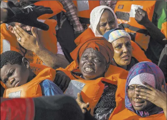  ?? Olmo Calvo The Associated Press ?? Migrants aboard a rubber dinghy off the Libyan coast on Saturday receive help from the Open Arms aid boat.