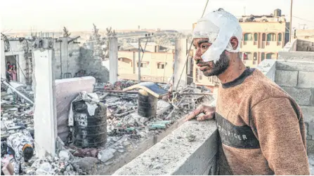  ?? — AFP photo ?? An injured man with a bandaged head looks on while standing next to the rubble and debris of a destroyed building in the aftermath of Israeli bombardmen­t on Rafah in the southern Gaza Strip.