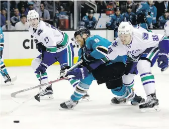  ??  ?? Sharks forward Joe Pavelski and Canucks defenceman Nikita Tryamkin fight for the puck during the second period in San Jose on Tuesday night.