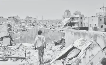  ??  ?? A Syrian boy walks amid the rubble of destroyed buildings in the northern city of Aleppo, which was recaptured by government forces in December 2016. — AFP photo