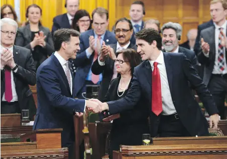  ??  ?? Finance Minister Bill Morneau, left, shakes hands with Prime Minister Justin Trudeau after reading Wednesday’s budget.