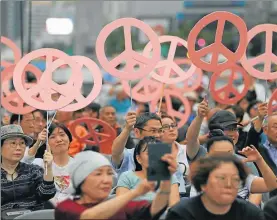  ??  ?? Las banderas de Estados Unidos y Corea del Norte en el frente del Fullerton Hotel. En Seúl hubo marchas para pedir que el encuentro marquel inicio de un proceso de paz. Controles policiales en la isla de Sentosa.