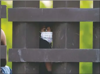  ?? (AP/Julio Cortez) ?? A migrant child looks through the U.S.-Mexico border fence as a group is processed and taken into custody while trying to sneak across the border in Abram-Perezville, Texas.