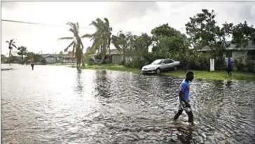  ?? SPENCER PLATT/GETTY IMAGES/AFP ?? A teen walks through flooded streets the morning after Hurricane Irma swept through the area yesterday in Naples, Florida.