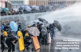  ??  ?? > Pro-democracy protesters are hit by a water cannon in Hong Kong, China, yesterday