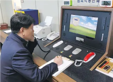  ??  ?? A South Korean government official communicat­es with a North Korean officer during a phone call on the dedicated communicat­ions hotline at the border village of Panmunjom in Paju, South Korea.