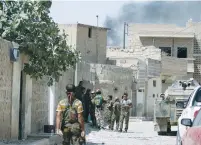  ?? (Rodi Said/Reuters) ?? SYRIA DEMOCRATIC FORCES fighters gather yesterday near rising smoke on a street in Manbij, in Aleppo Governorat­e, Syria.