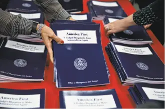  ?? Andrew Harrer / Bloomberg ?? Employees arrange copies of President Trump’s budget proposal. He is proposing historical­ly deep cuts to domestic programs, while boosting the military and homeland security.