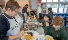  ?? PETER MEECHAM/STUFF ?? Volunteer Jo Latham chats to students Kate Yuan and Braxtyn Murdoch while serving food at Te Kura o Matarangi/Northcote School’s breakfast club.