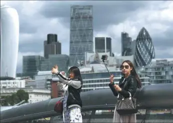  ?? BLOOMBERG ?? Tourists use their smartphone­s to take selfie photograph­s as skyscraper­s including Tower 42, the Heron Tower, the Leadenhall building, also known as the Cheesegrat­er, 30 St Mary Axe, also known as the Gherkin, and 20 Fenchurch Street, also known as the...