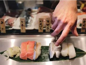  ?? THE ASSOCIATED PRESS ?? A chef serves sushi at a restaurant in Tokyo. As these fearless foodies come of age, they are giving the restaurant industry plenty to chew on.