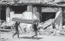  ?? AGENCE FRANCE-PRESSE ?? Left: Palestinia­n men carry a mattress past the rubble of a building destroyed in a previous Israeli bombardmen­t on Monday.