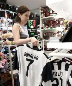  ??  ?? A saleswoman hangs Cristiano Ronaldo’s Juventus jersey in a shop in downtown Turin.