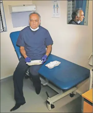  ?? (AP/Frank Augstein) ?? Dr. Anil Mehta poses for a photograph as he prepares syringes at his practice in Northeast London.
