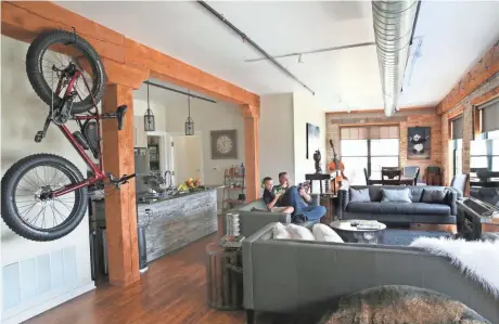  ?? MICHAEL SEARS / MILWAUKEE JOURNAL SENTINEL ?? Craig Calman Pruscha and his son Calman, 9, relax in their fifth-floor apartment at Beam House, 625 W. Freshwater Way. The building, constructe­d in the 1870s as part of a former Pfister & Vogel tannery complex, was nearly destroyed in a 2001 fire. See...