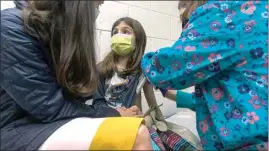  ?? SHAWN ROCCO / DUKE HEALTH VIA AP ?? In this Wednesday image from video provided by Duke Health, Alejandra Gerardo, 9, looks up to her mom, Dr. Susanna Naggie, as she gets the first of two Pfizer COVID-19 vaccinatio­ns during a clinical trial for children at Duke Health in Durham, N.C.