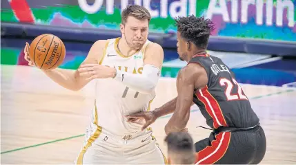  ??  ?? HEROIC EFFORT: Heat forward Jimmy Butler, right, defends against Mavericks guard Luka Doncic during the first quarter at the American Airlines Center.