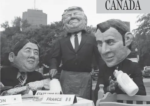  ?? LARS HAGBERG / AFP / GETTY IMAGES ?? Members of the global poverty eradicatio­n group OXFAM, dressed as Japanese Prime Minister Shinzo Abe, left, U.S. President Donald Trump and French President Emmanuel Macron, pose for pictures outside Quebec City’s legislatur­e ahead of the G7 summit on...